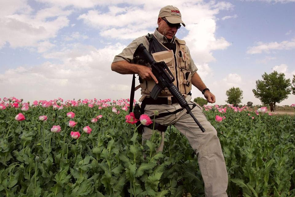 An American security contractor walked through an opium poppy field near Lashkar Gah in Helmand province of southern Afghanistan.