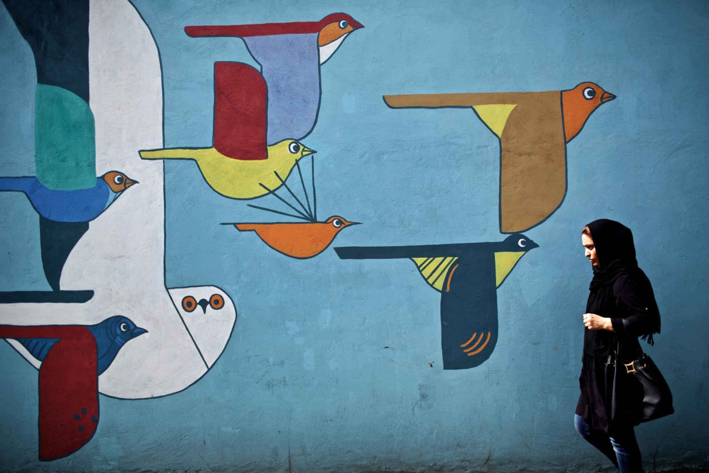 An Iranian woman walks past a mural in Tehran on June 29, 2015. Behrouz Mehri (AFP/Getty Images)